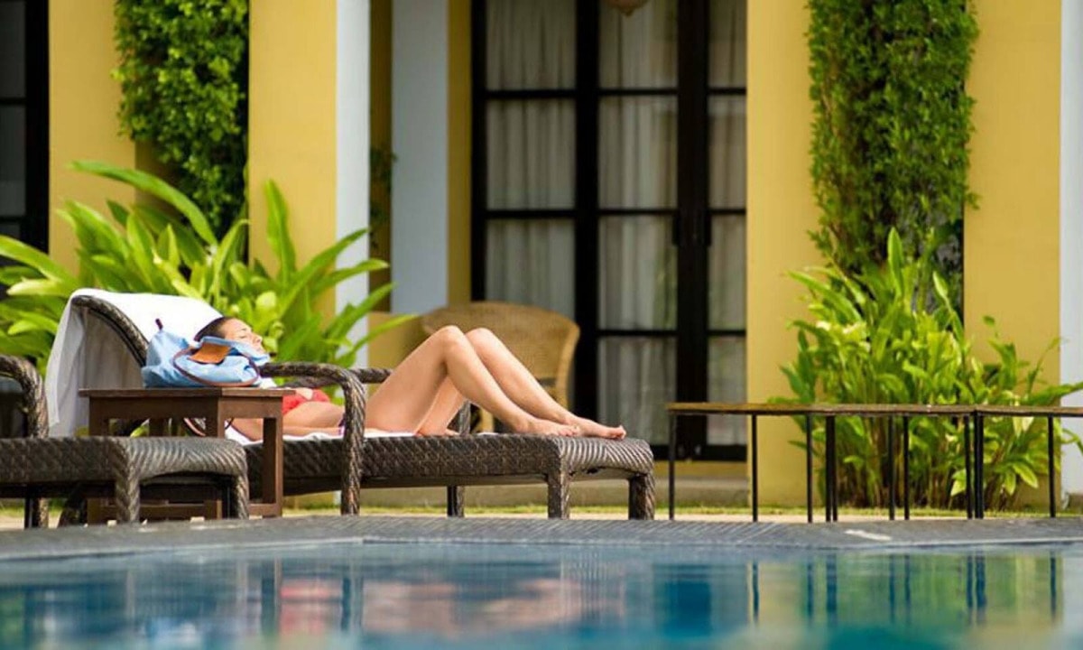 Courtes vacances avec spa dans un hôtel - femme allongée sur un transat au bord de la piscine